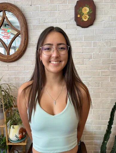 Smiling client with long, straight dark brown hair and glasses