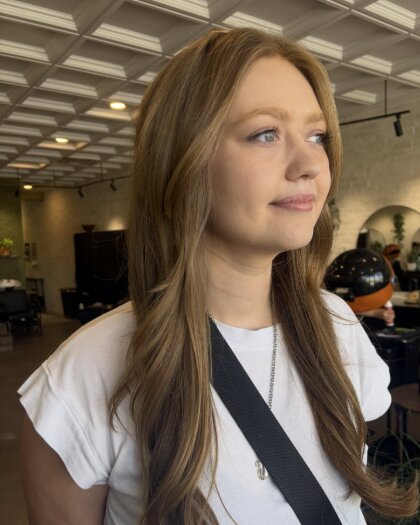 Client with a long, layered face-framing cut in warm light brown