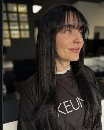 Client with long black hair and wispy bangs, in profile
